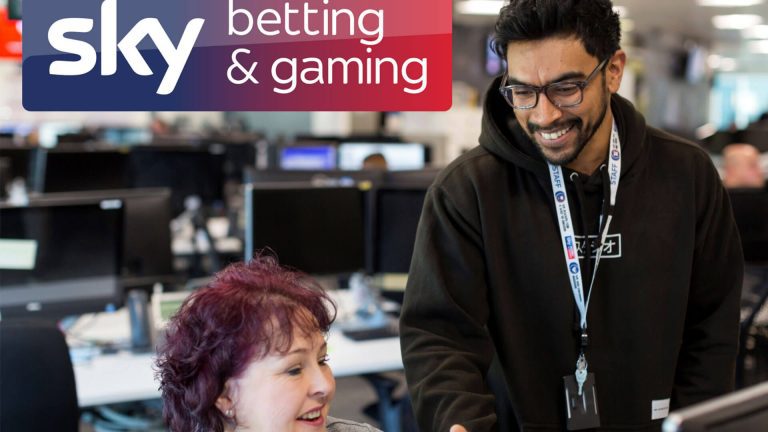 man and woman in skybet office discussing works in busy office space.