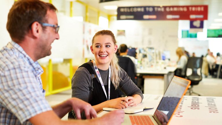 Woman in discussion with male coworker in sky bet offices.